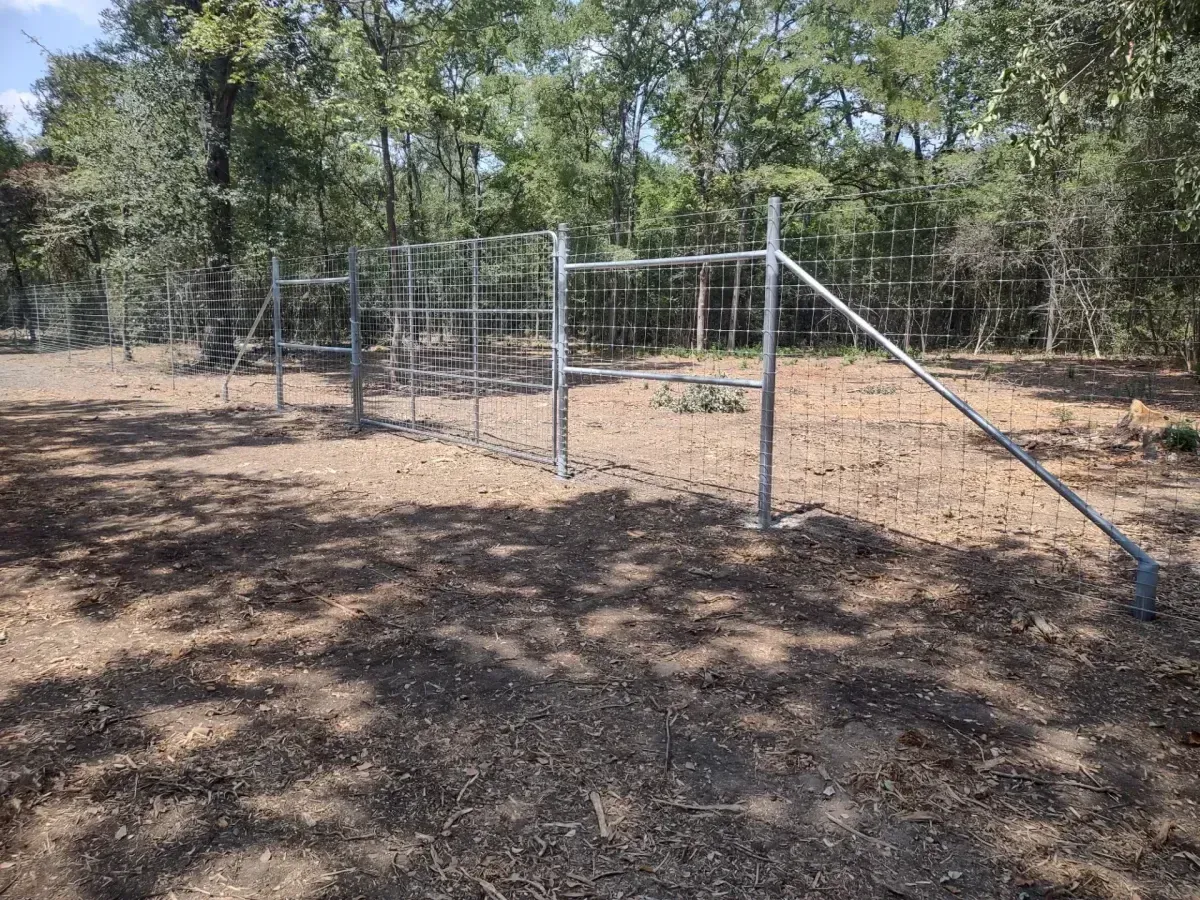 Metal wire fence installation along wooded property line