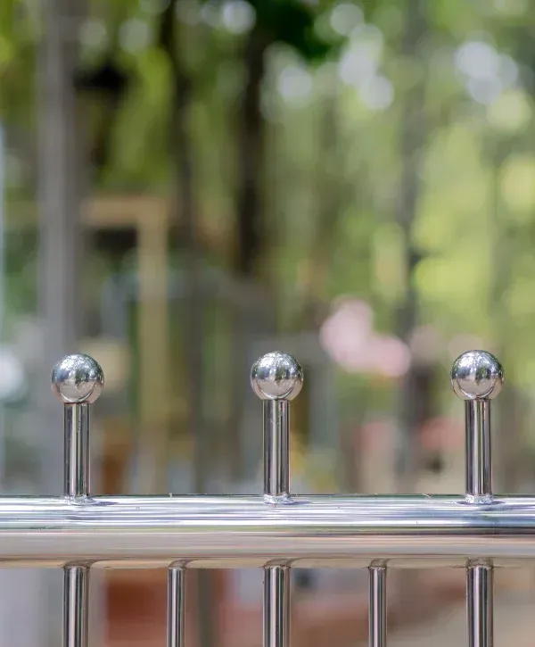 Close-up of polished stainless steel fence design with decorative posts.