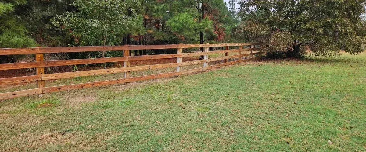 Wooden ranch-style fence installed along green yard and trees