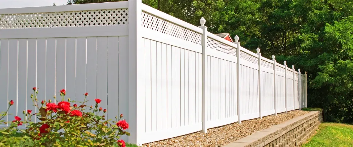 Decorative white vinyl privacy fence with lattice top and garden flowers.