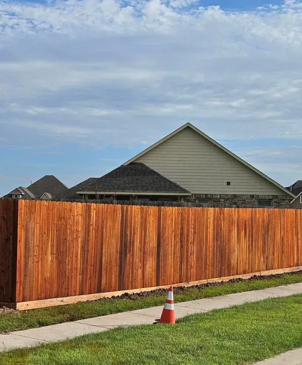 Newly installed wooden privacy fence alongside a neighborhood sidewalk