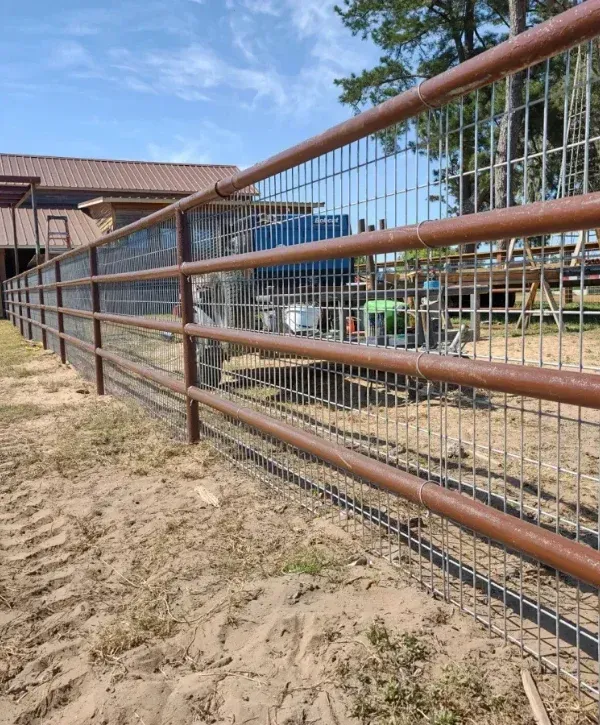 Metal livestock fence enclosing ranch property with barn