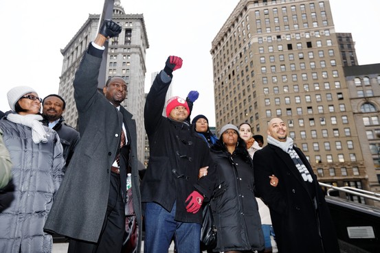 A candid photo of a diverse group of people gathered in a community center, engaged in a discussion about justice reform. The group includes young adults and elders, with visible notepads and advocacy materials, set against a bright, welcoming interior. The atmosphere is collaborative and hopeful.