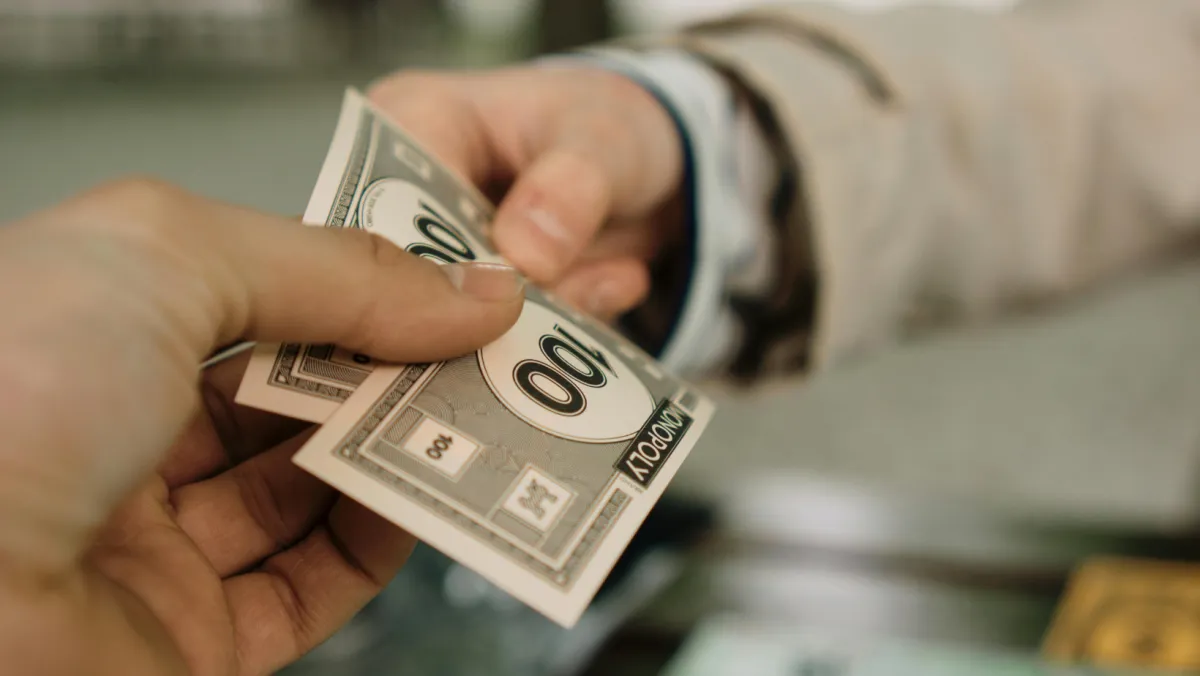 Photo of two one hundred dollar bills in monopoly money.