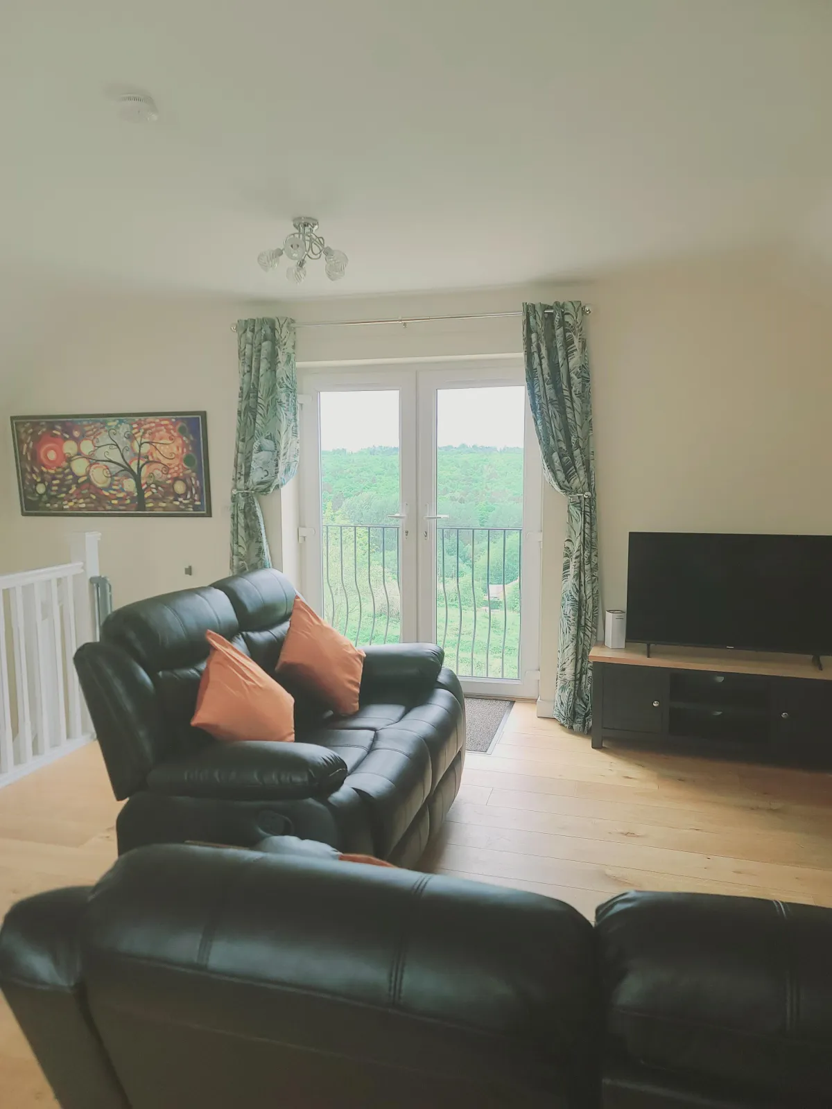 living space with reclining chairs, electric log burner, smart tv, wifi and juliet balcony with forest views