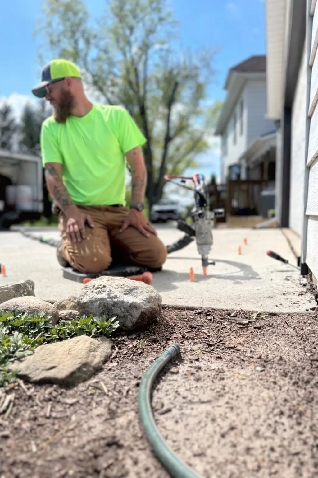 man kneeling while fixing concrete slab with mudjacking tools