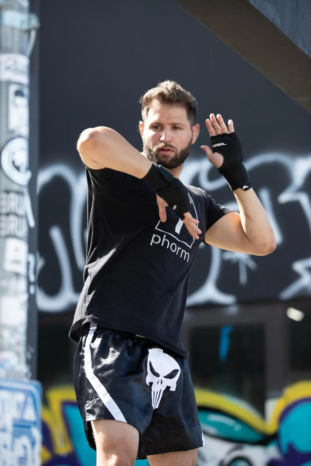 Paul Puleo, owner of Fight Fit and private martial arts instructor, seen in a fighting stance and sitting while wrapping his gloves. Personal trainer specializing in martial arts.