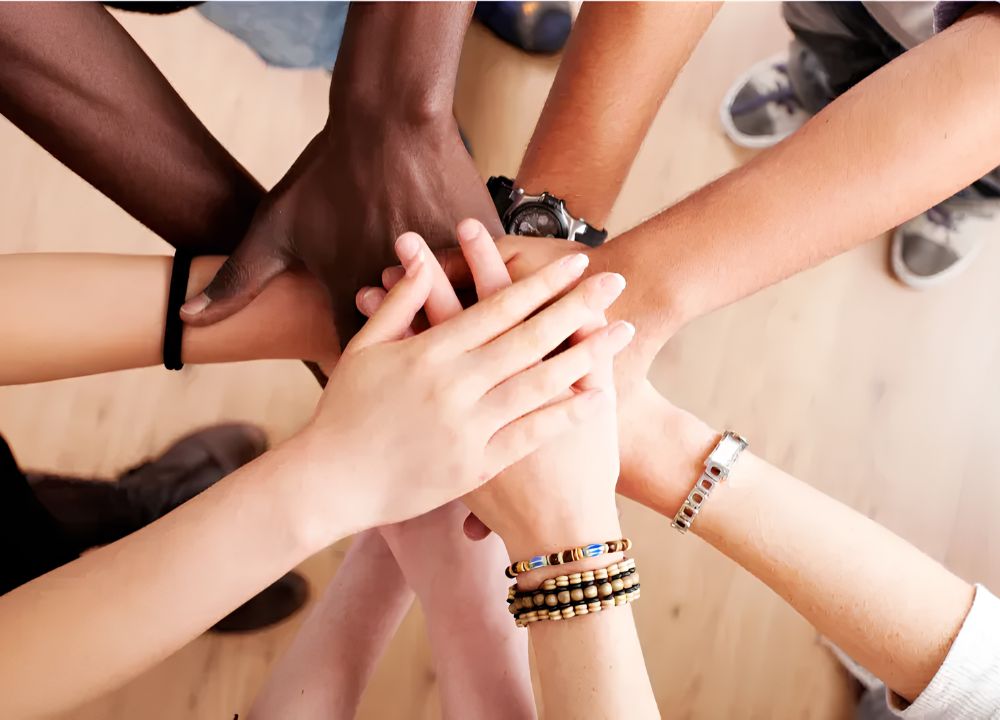 Diverse group of hands coming together representing the community and support network at Breakthrough Functional Medicine in Wilmington NC