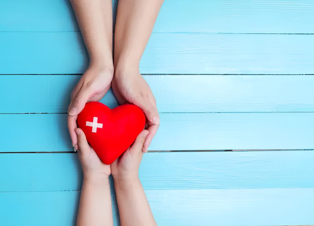 Two sets of hands holding a red heart representing compassionate functional medicine and heart health support at Breakthrough Functional Medicine
