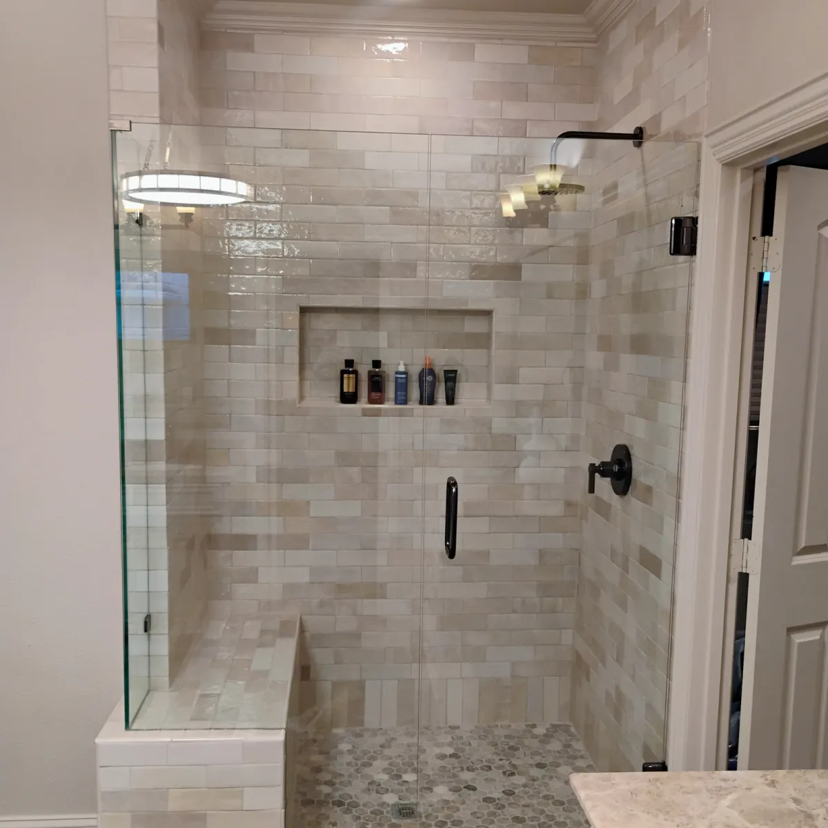 Walk-in frameless shower with bench and chandelier