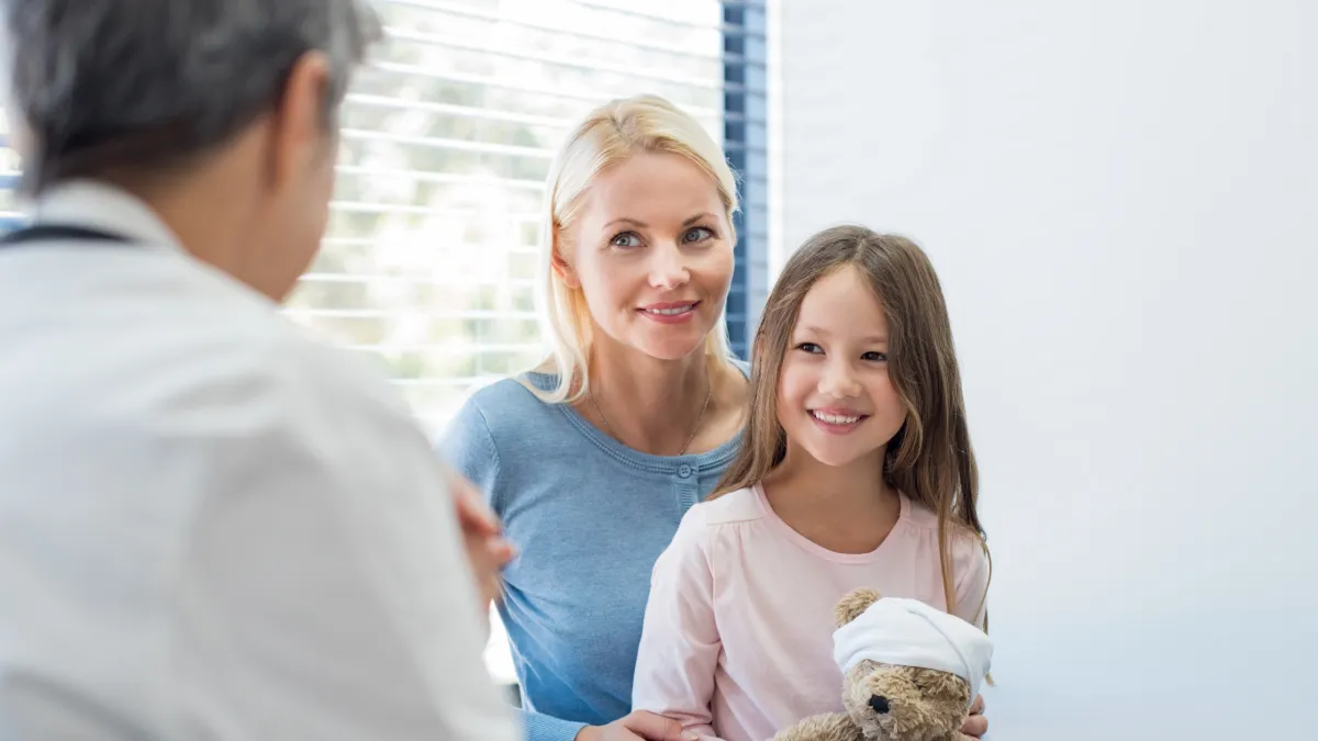 Pediatra conversando com os pais durante consulta, representando cuidado integral e acompanhamento infantil.