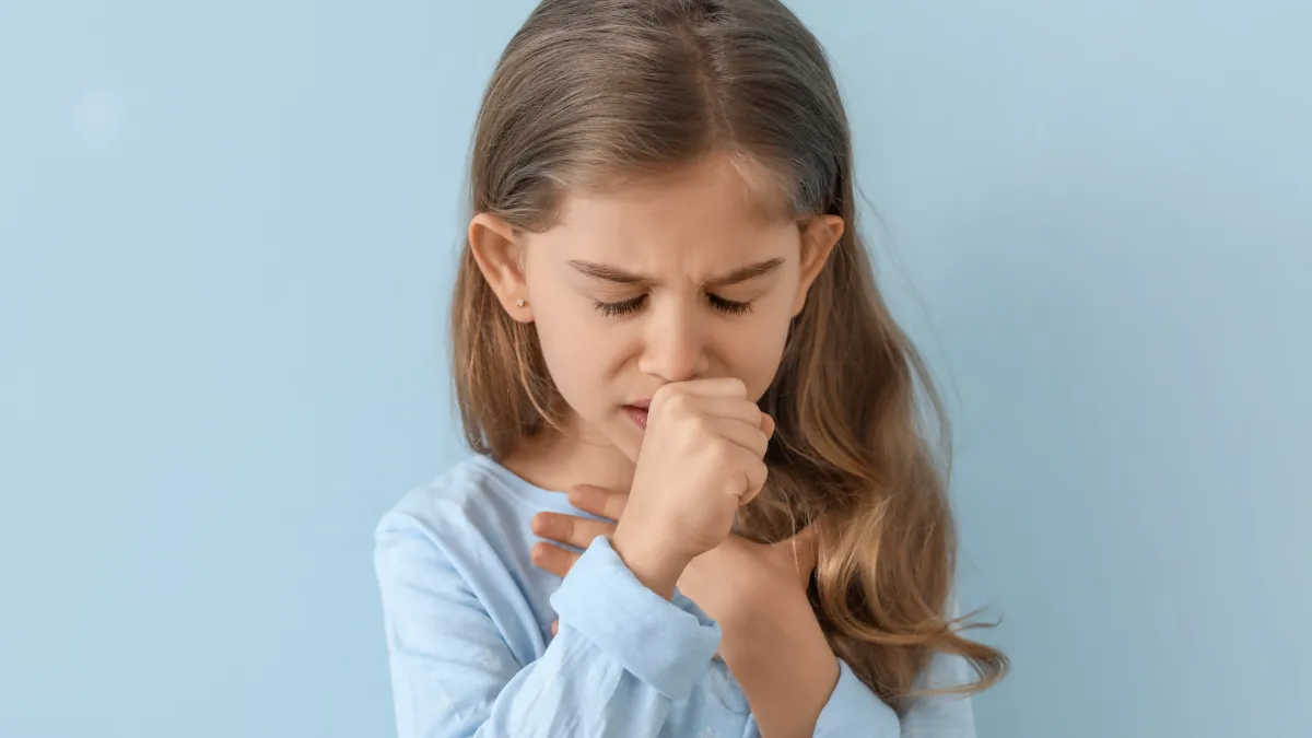 Criança com tosse leve sendo cuidada pelos pais em ambiente acolhedor.