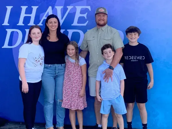 Family of six posing in front of a blue backdrop that says 'I Have Decided'