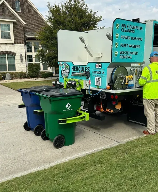Blue and green waste bins placed in front of Hercules Power Clean truck on a residential street