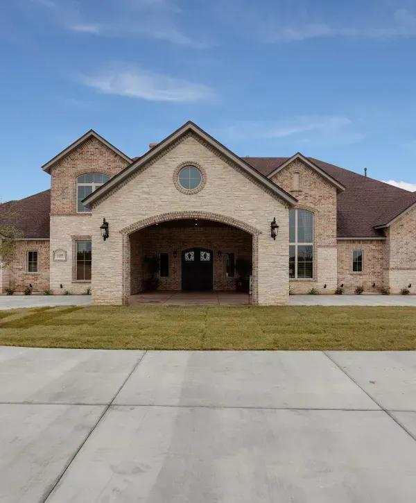 Luxury suburban brick home with wide driveway and green front yard