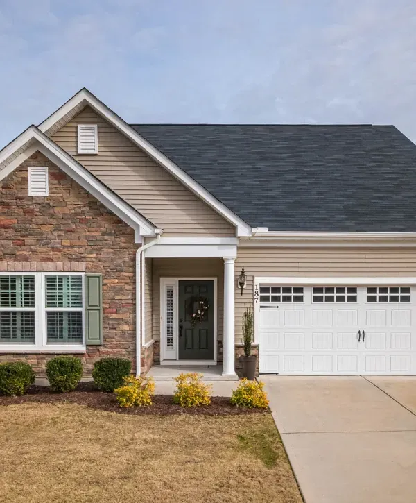 Curved concrete driveway leading to a large brick home with well-maintained landscaping