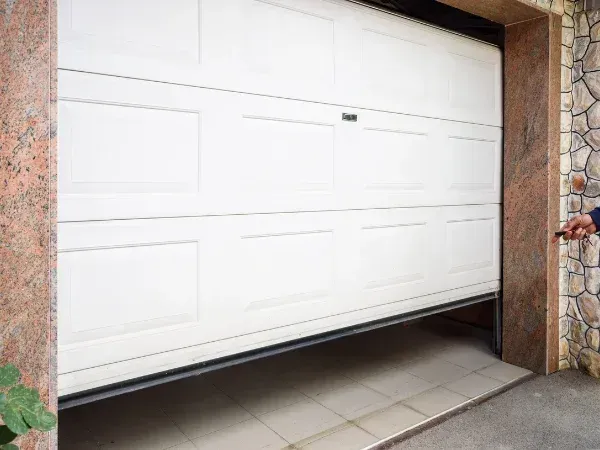 Residential garage door opening with stone exterior walls and tiled driveway.
