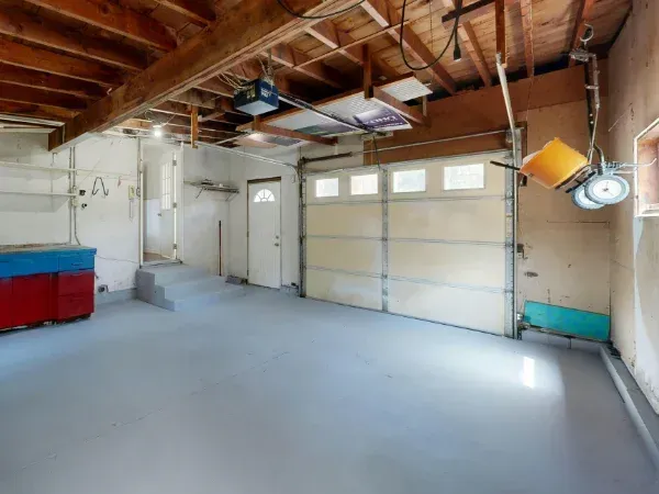 Clean and empty residential garage interior with concrete floor and closed garage doors.
