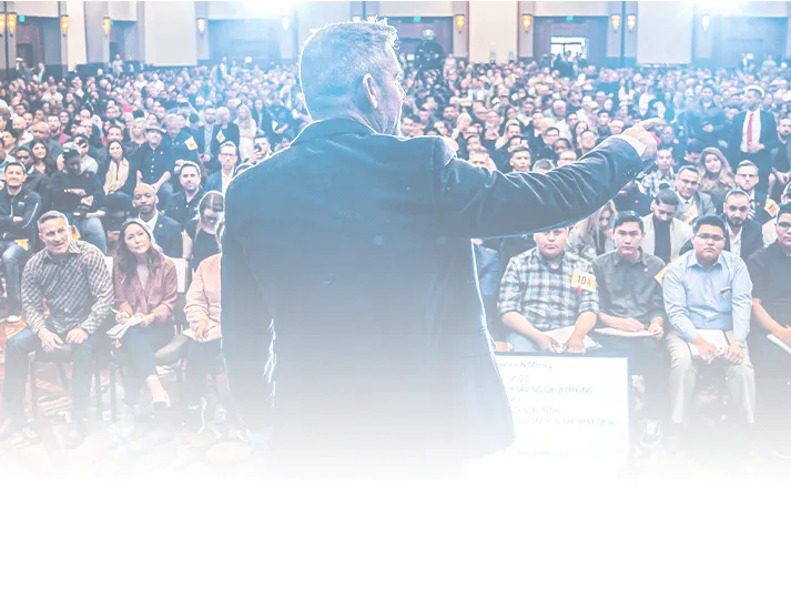 Grant Cardone standing in front of a live audience, delivering high-energy coaching during a 2-day real estate summit, helping attendees master strategies to scale their investments.