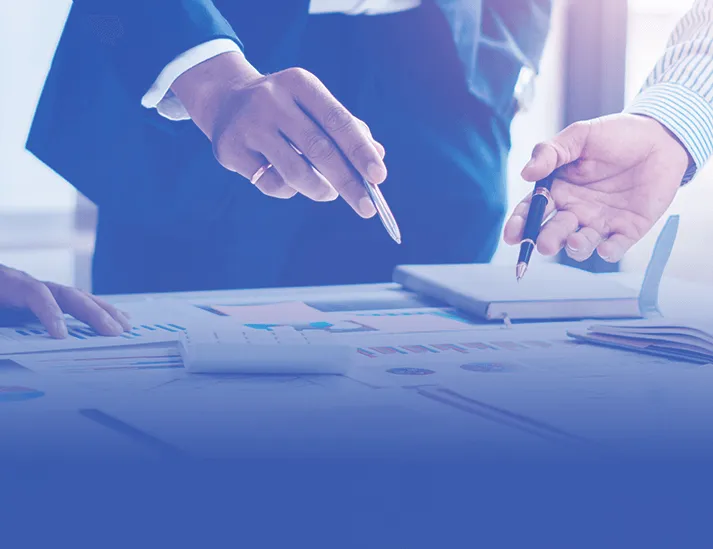 Three professionals in business attire pointing at notebooks and a map, collaborating on in- depth real estate investment strategies and planning winning deals.