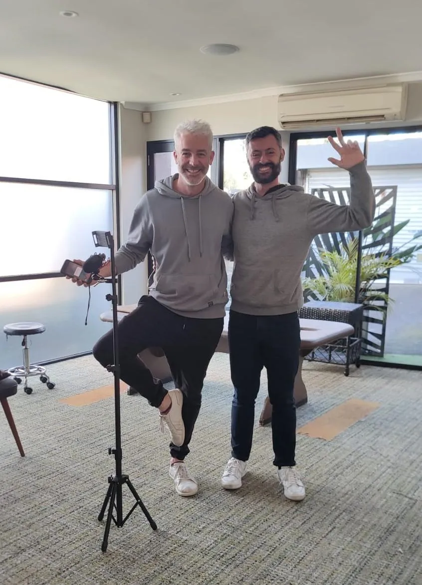 Photograph of Chris and Eduardo standing and waving inside the clinic.