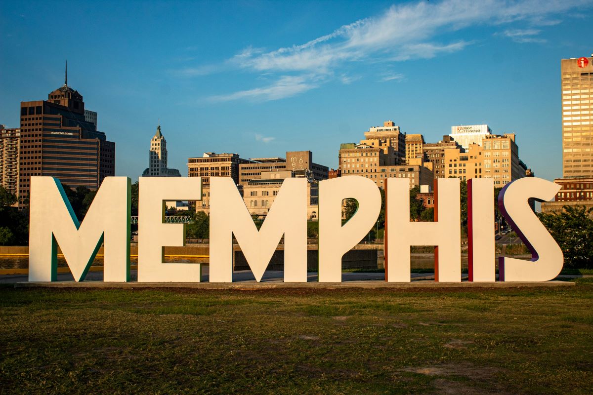 Families enjoying an outdoor spring festival in the Memphis area with vendor tents, live music, and sunny May weather.