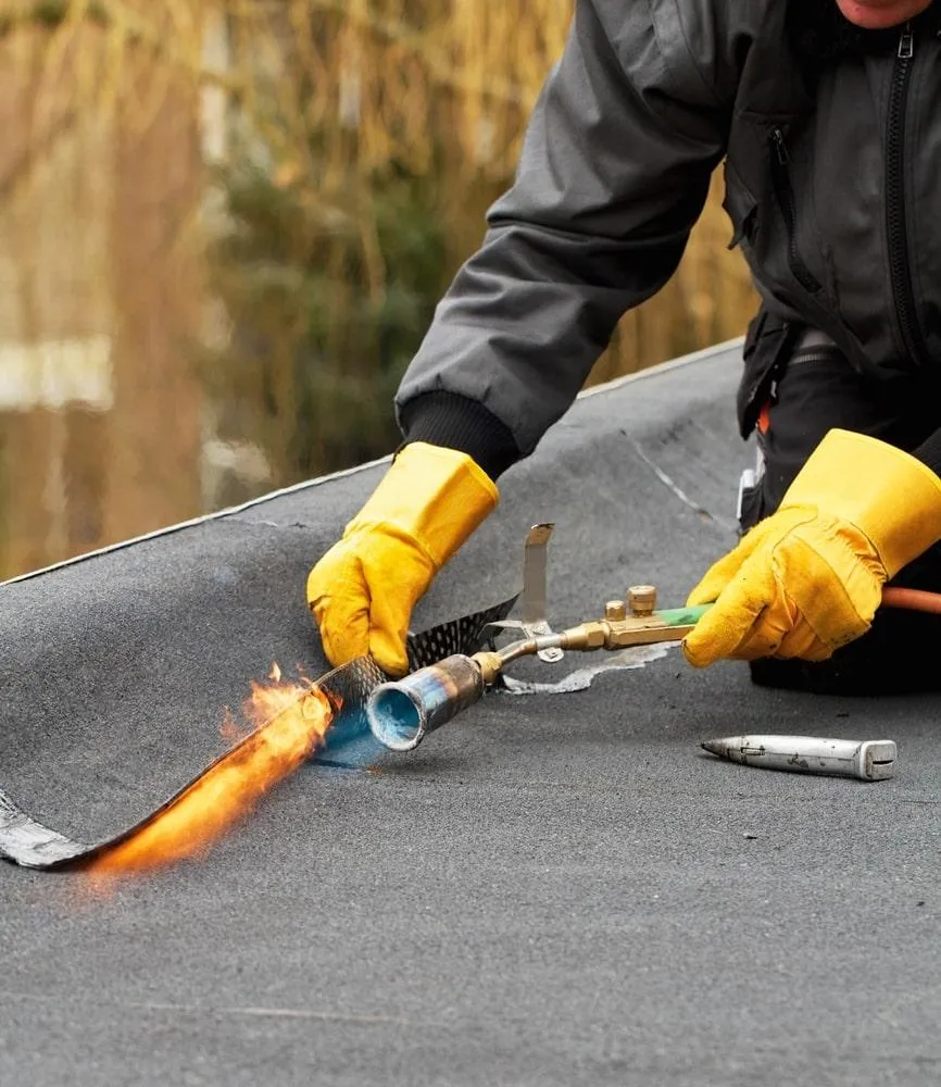 expert roofer applying modified bitumen on commercial roof