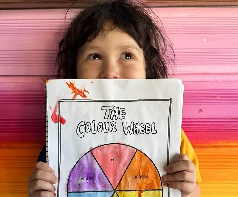 Landscape photo of a small group class: children at easels painting in bright studio light, candid composition, joyful atmosphere, natural colors.