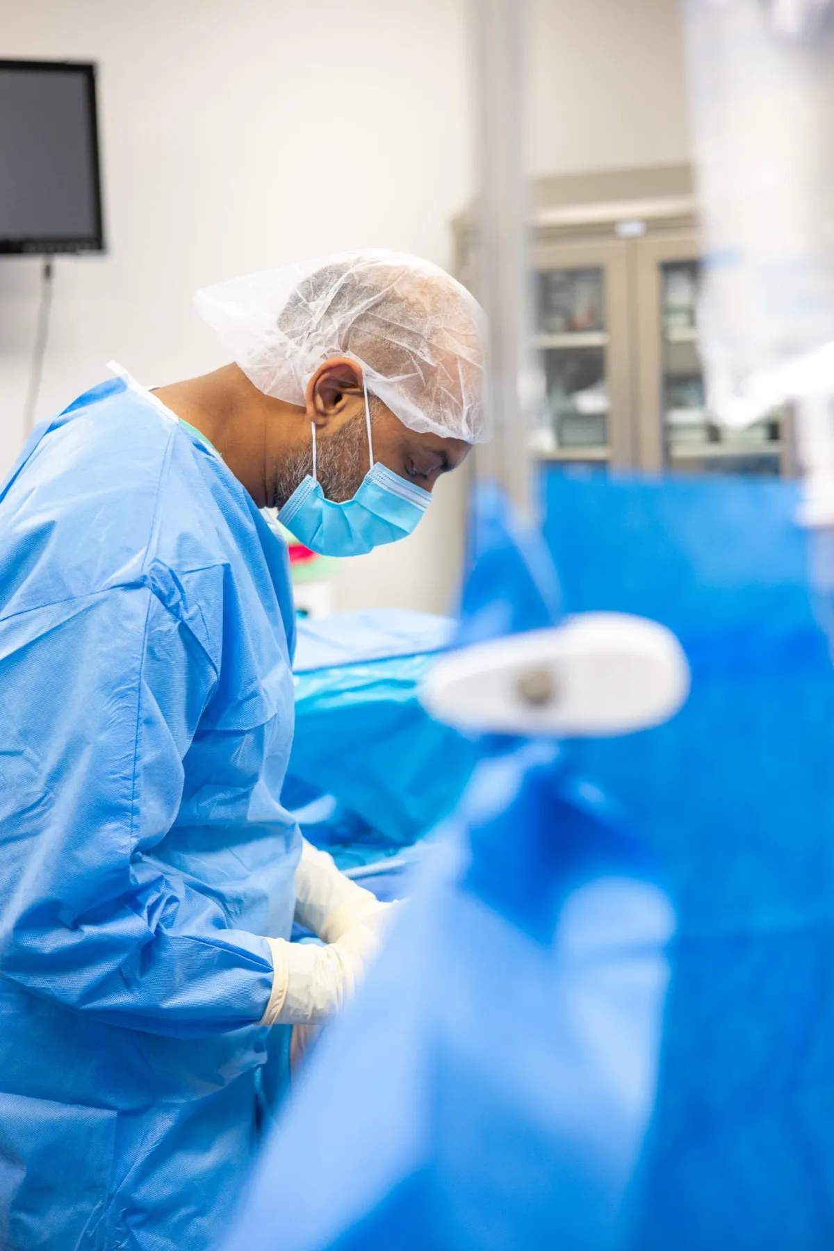 Dr. Shitel Patel, board-certified plastic surgeon at Lift Plastic Surgery in Houston, performing a precision cosmetic procedure in the operating room, dressed in blue surgical gowns.