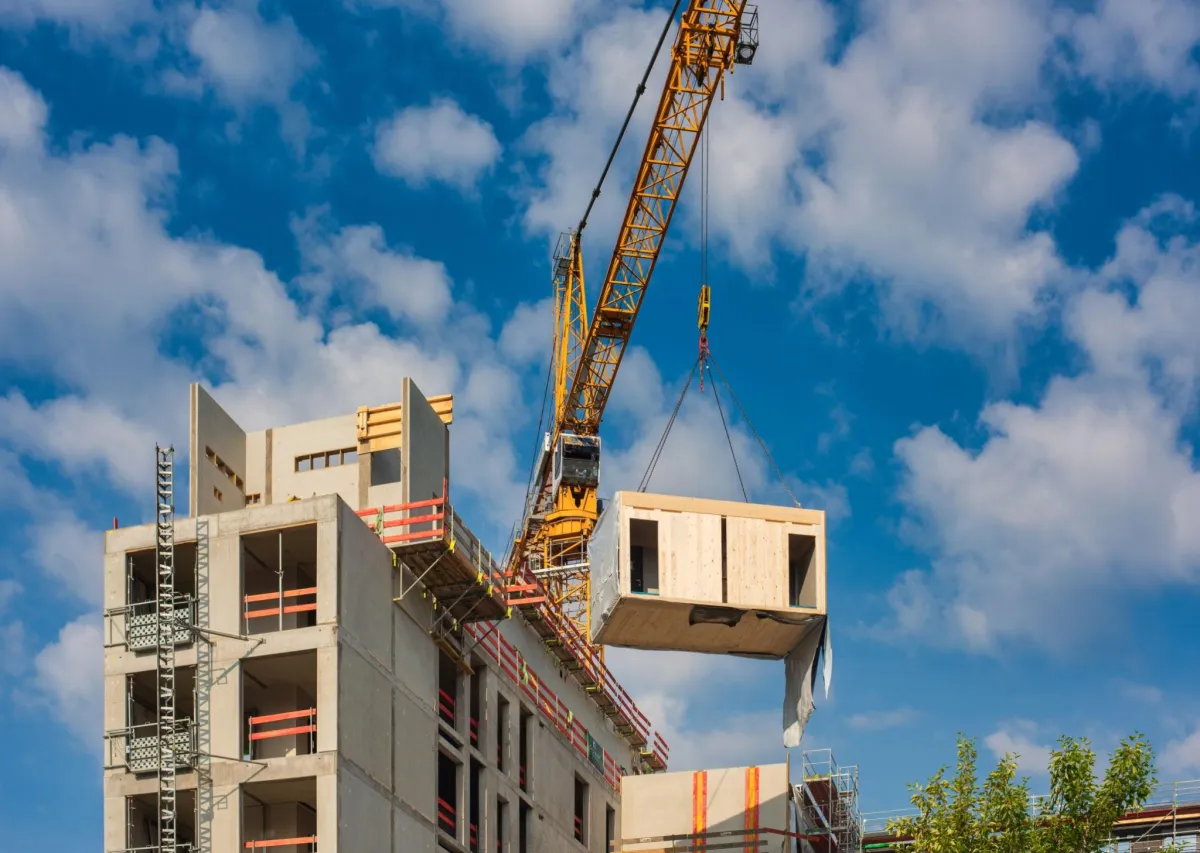 Prefabricated building module being lifted into place by a crane