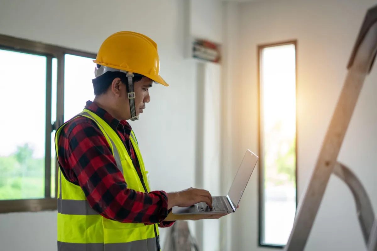 Construction manager entering report information into laptop