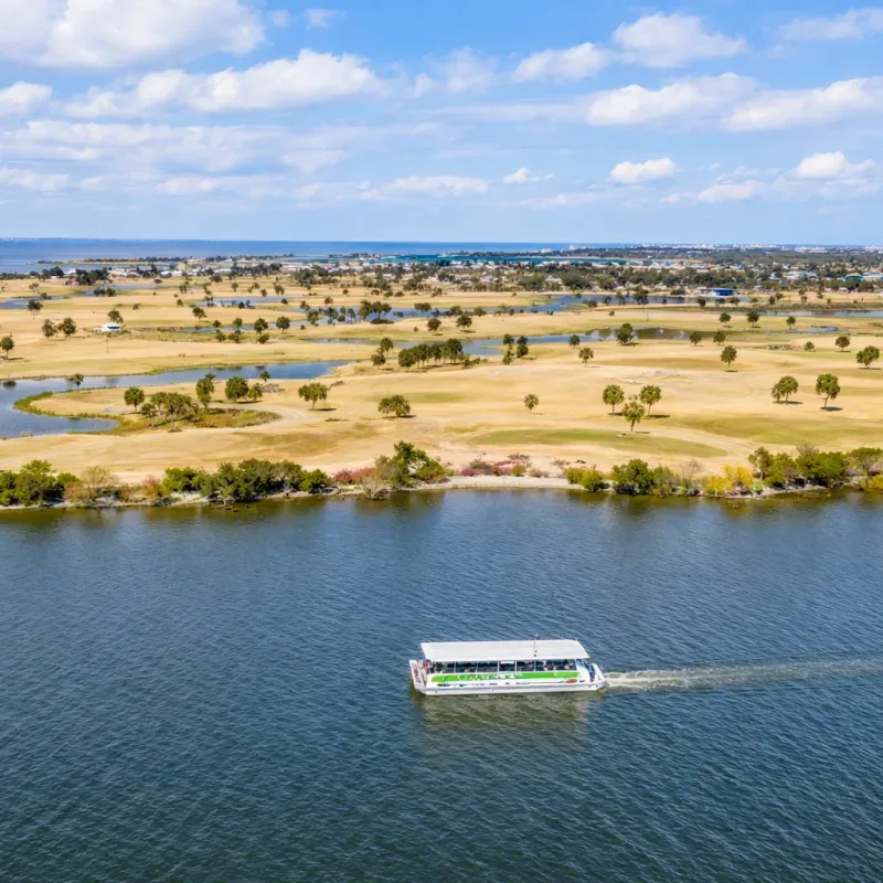 Aerial view of a catamaran sailing on the calm waters of Cocoa Beach, surrounded by lush landscapes and diverse ecosystems, highlighting eco-friendly sailing experiences and wildlife encounters.