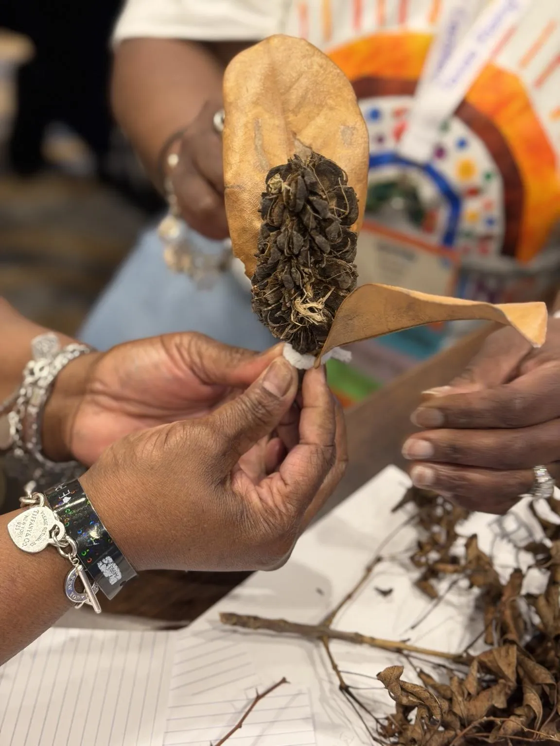 An educator holding a creation made from leaves and seed pods