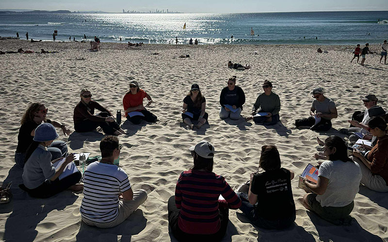 Elicia leading a circle on the beach