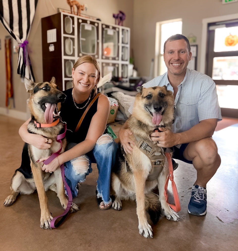 Owners of Ductman Air Conditioning & Heating, smiling while adopting two German Shepherds at a local animal shelter in New Braunfels, Texas, showing their love for community and family values.