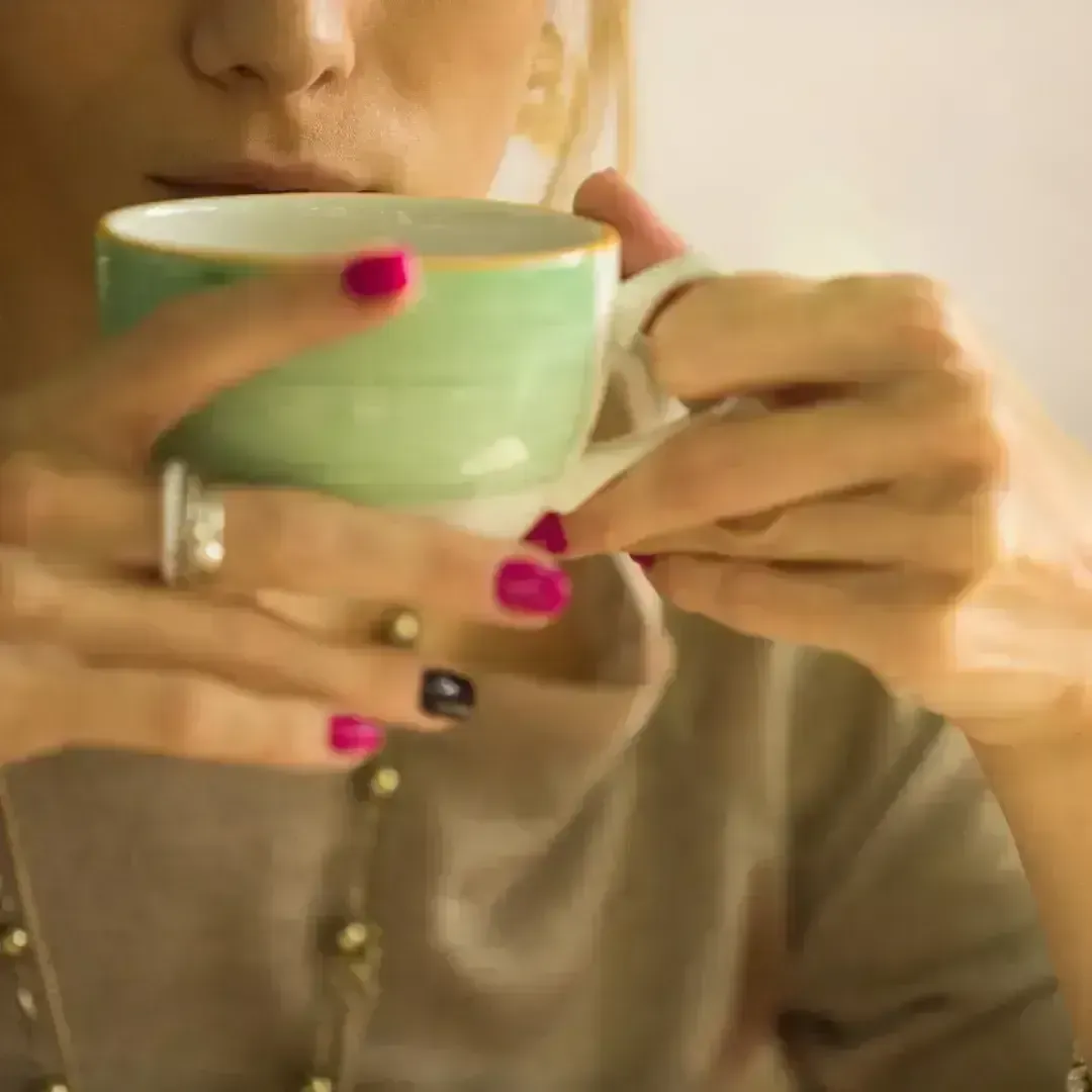 Woman peacefully sipping tea during a money healing ritual, symbolizing safety, calm, and abundance with Evelyn Foreman.