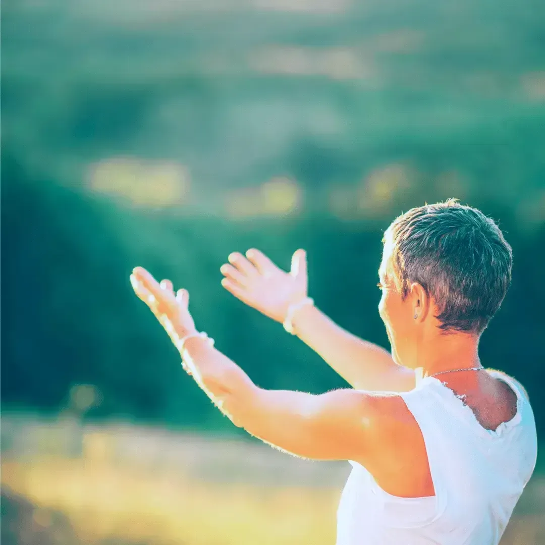 Woman standing in an open field with arms raised, symbolizing emotional release, clarity, and renewed trust in the Money Shift Detox process.