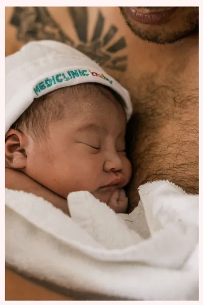 Image of a baby being held skin to skin with its father’s chest, shortly after being born by. Image corresponds with a list of what is included in private birth education classes in Minneapolis and Saint Paul, Minnesota.