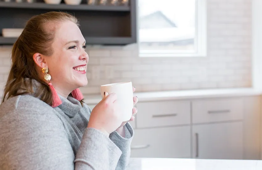desktop version of fertility coach Jillian Carpenter, drinking coffee and smiling