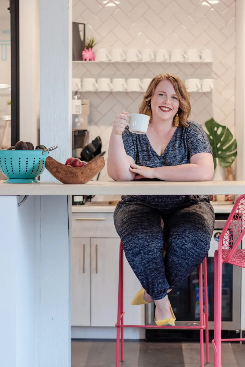 An image of Twin Cities doula, Jillian Carpenter, drinking coffee and smiling at a location in Minneapolis, Minnesota.