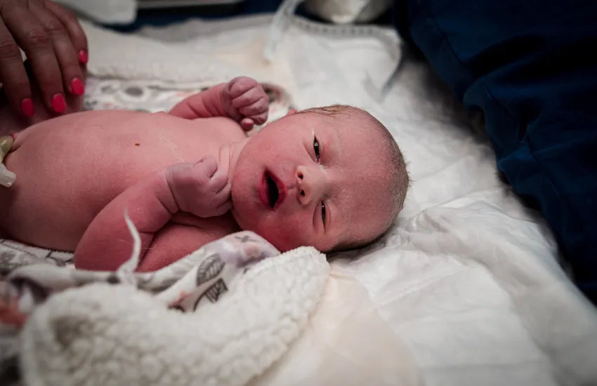 A baby being born in the water during a doula supported birth. Image to support testimonial from Jess in Minneapolis, Minnesota.