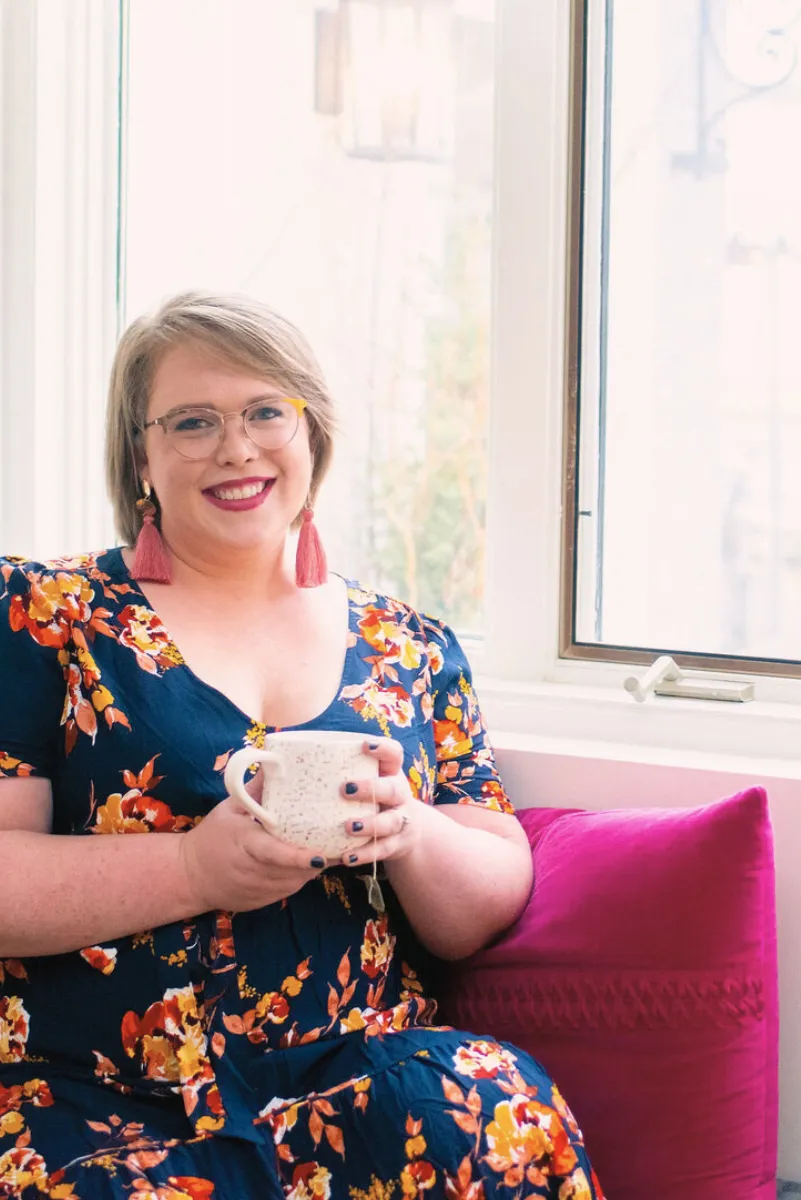 An image of Twin Cities doula, Jillian Carpenter, drinking coffee and smiling at a location in Minneapolis, Minnesota.