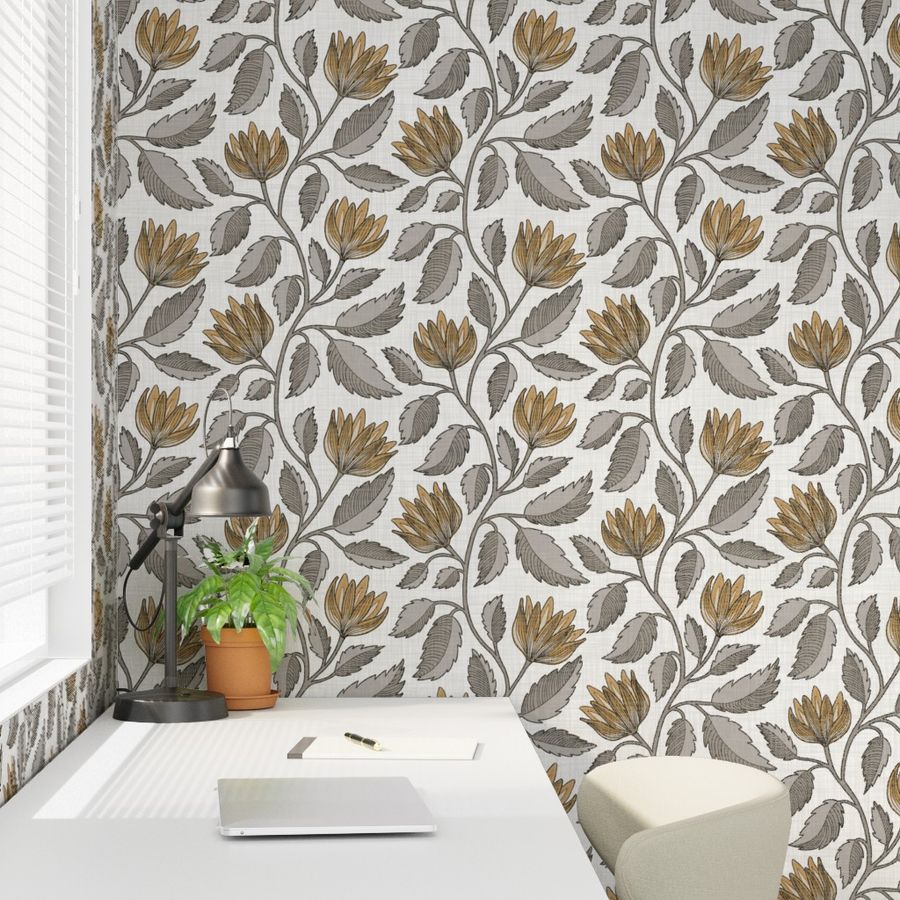 Muted ochre and gray floral vine wallpaper creates a botanical feature wall in a calm home office with a desk, lamp, and plant.