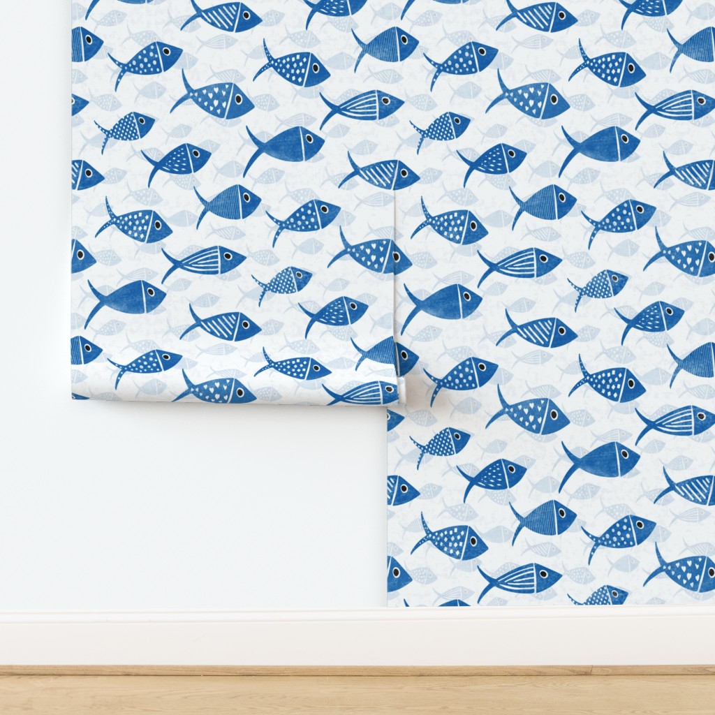 Blue and white Nautical School of Fish wallpaper shown across adjoining walls with varied hand-drawn fish over pale fish silhouettes.