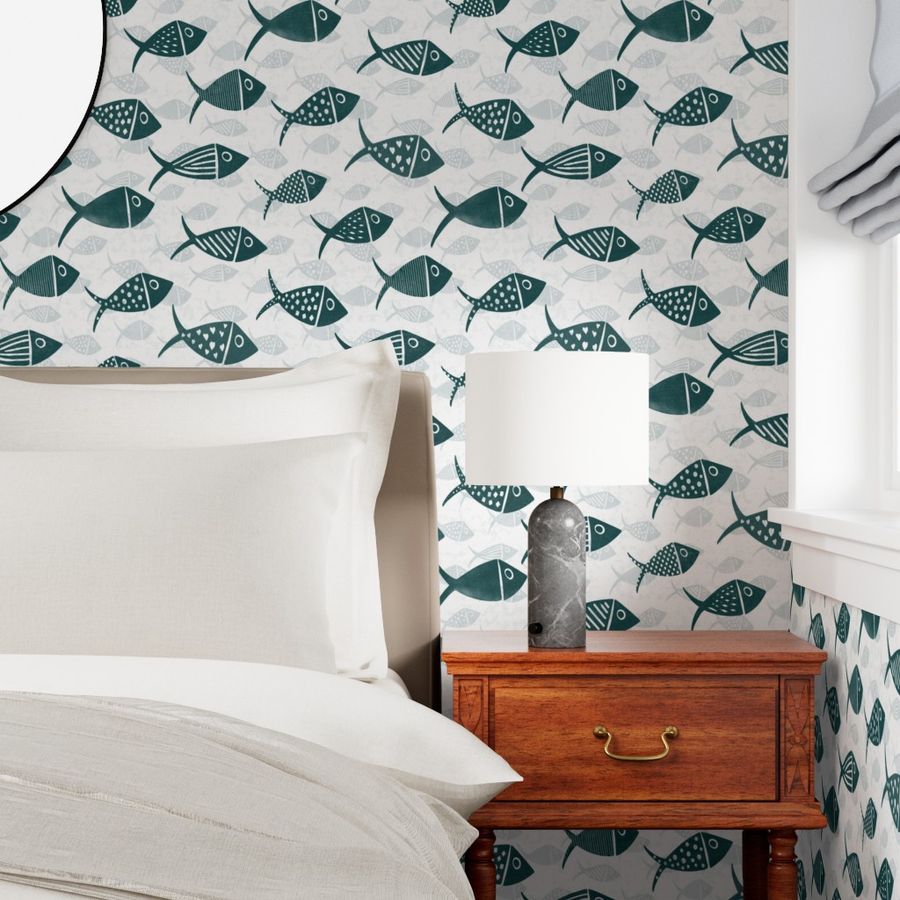 Teal and white Nautical School of Fish wallpaper in a bedroom with a white bed, wooden nightstand and hand-drawn fish repeat.