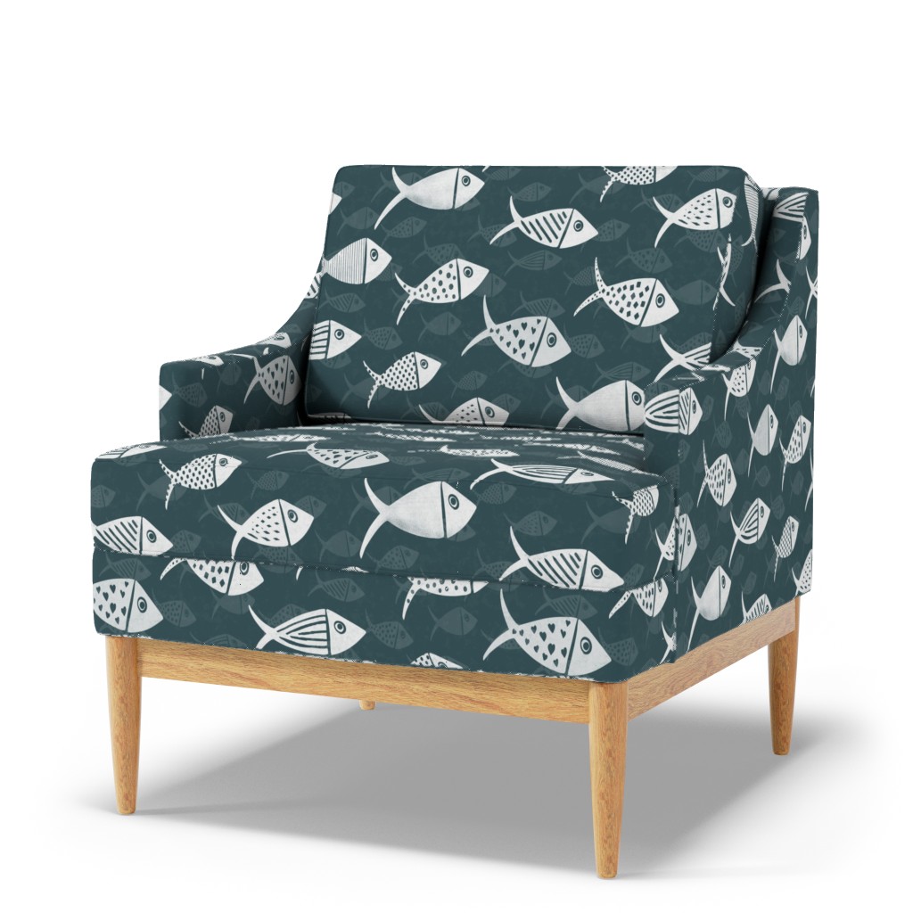 Dark teal Nautical School of Fish shown on an upholstered armchair with white fish and subtle tonal fish in the background.