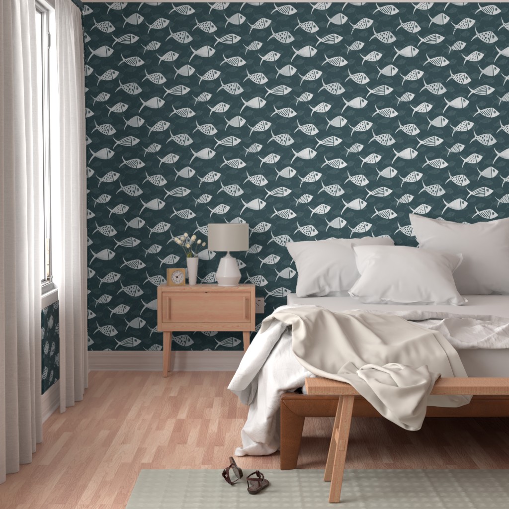 Dark teal Nautical School of Fish wallpaper in a bedroom with white fish, wooden bedside table and neutral bedding.