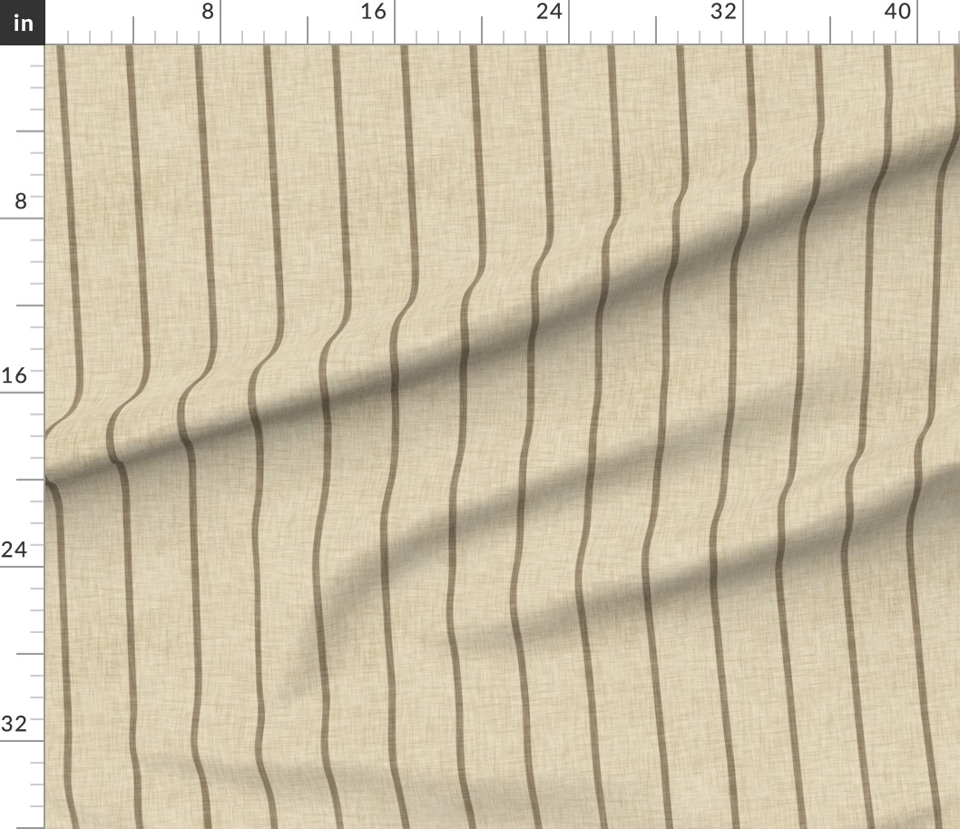Warm beige striped fabric draped beneath a measurement ruler, showing narrow taupe lines and a woven linen-look surface.