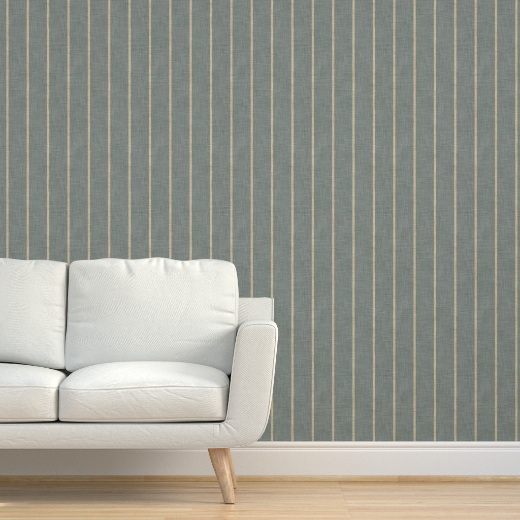 Slate blue-grey Roselk Design wallpaper with fine beige vertical stripes and a woven linen-look texture behind a light grey sofa.
