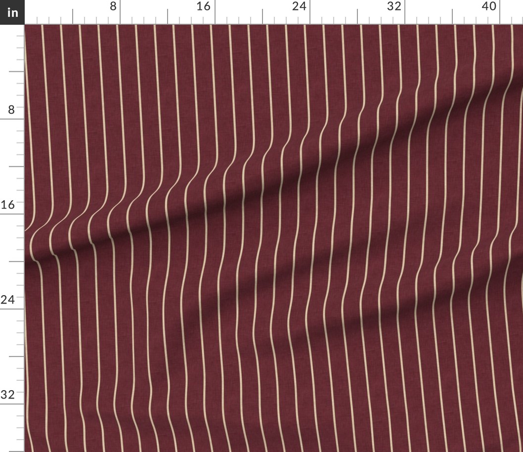 Deep burgundy striped fabric draped below a ruler, showing fine cream vertical lines and the linen-look surface.